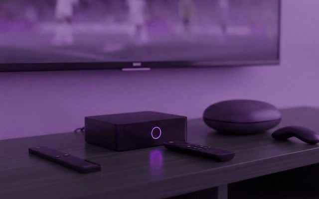 A streaming stick, a set-top box and a round streaming box with their remotes on a TV console