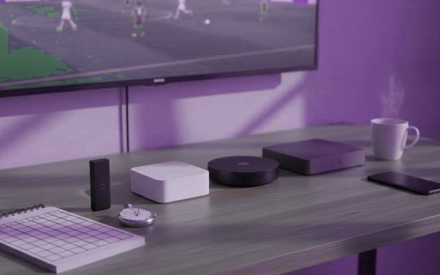 Five streaming devices, a notebook scoring grid and a stopwatch in front of a TV showing a football match