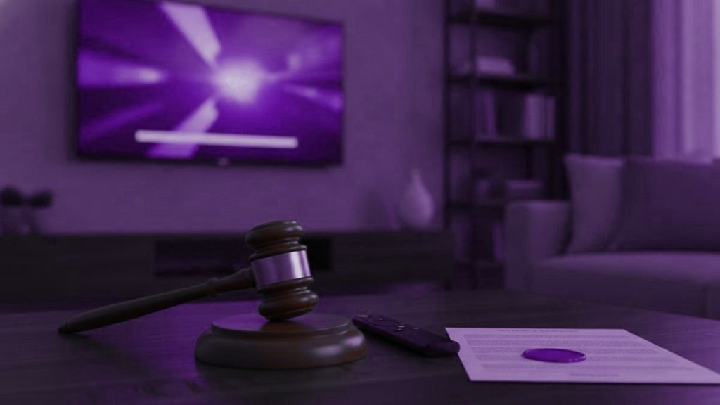 A judge gavel, a streaming remote and a sealed document on a coffee table in front of a TV